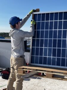 Solar installer on the roof of Whittier Elementary removes packaging from solar panels 