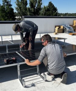Two men installing solar panels on the rooftop at Whittier Elementary School in Boise Idaho