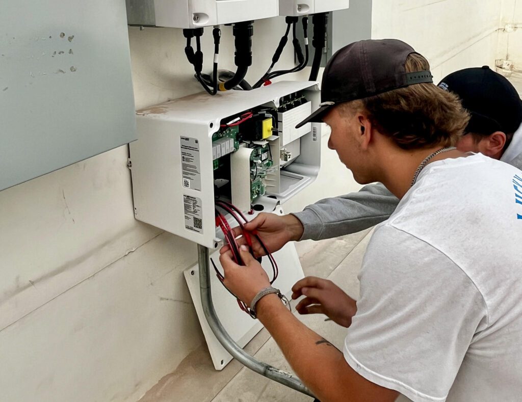 Two men work to service a solar energy system