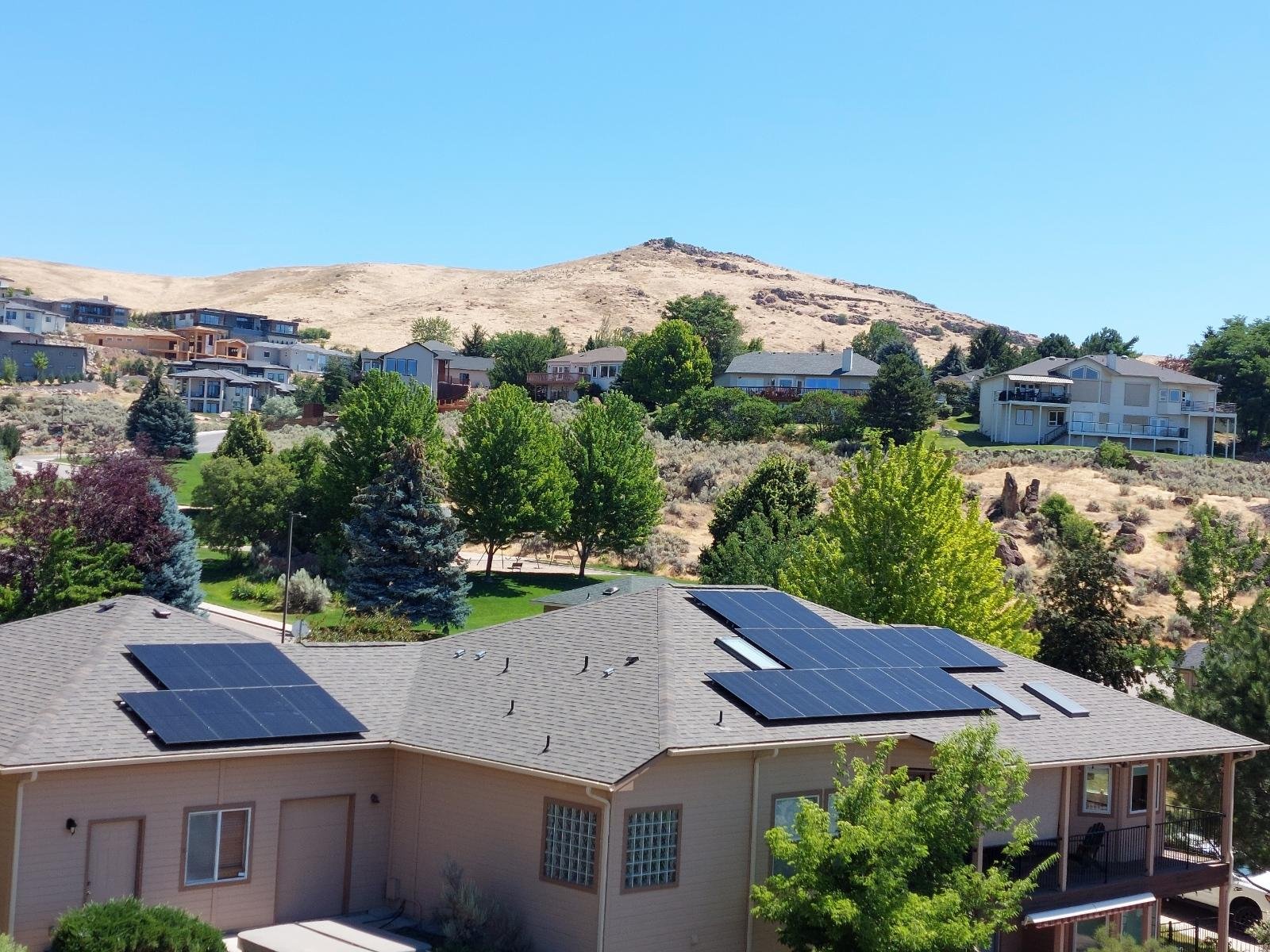 View of the Boise foothills with houses and trees on the hill in the background and a home with rooftop solar in the foreground